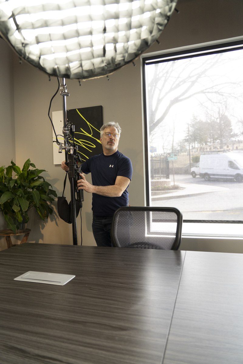 Len Marks adjusting a lighting rig while planning an on-site headshot session